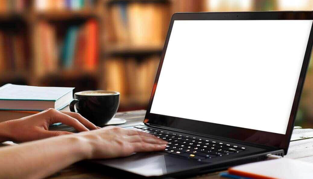 person working on laptop at desk with coffee cup