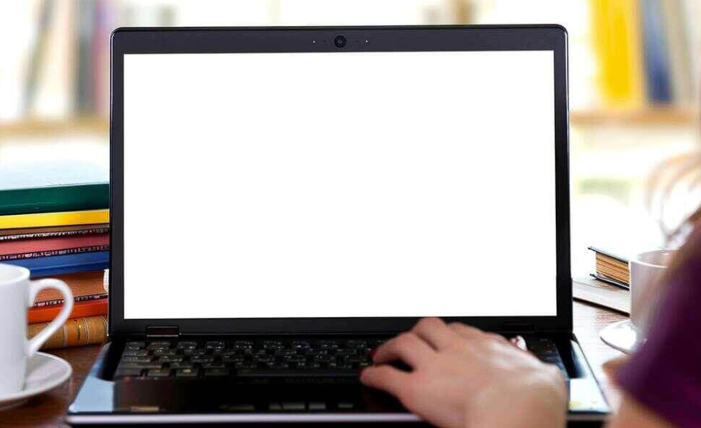 woman working on laptop with books and coffee cups